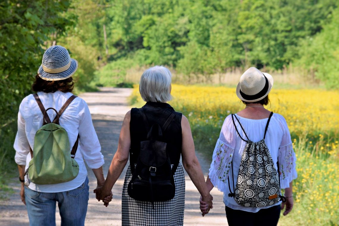 Drei Frauen gehen Hand in Hand im Sommer spazieren
